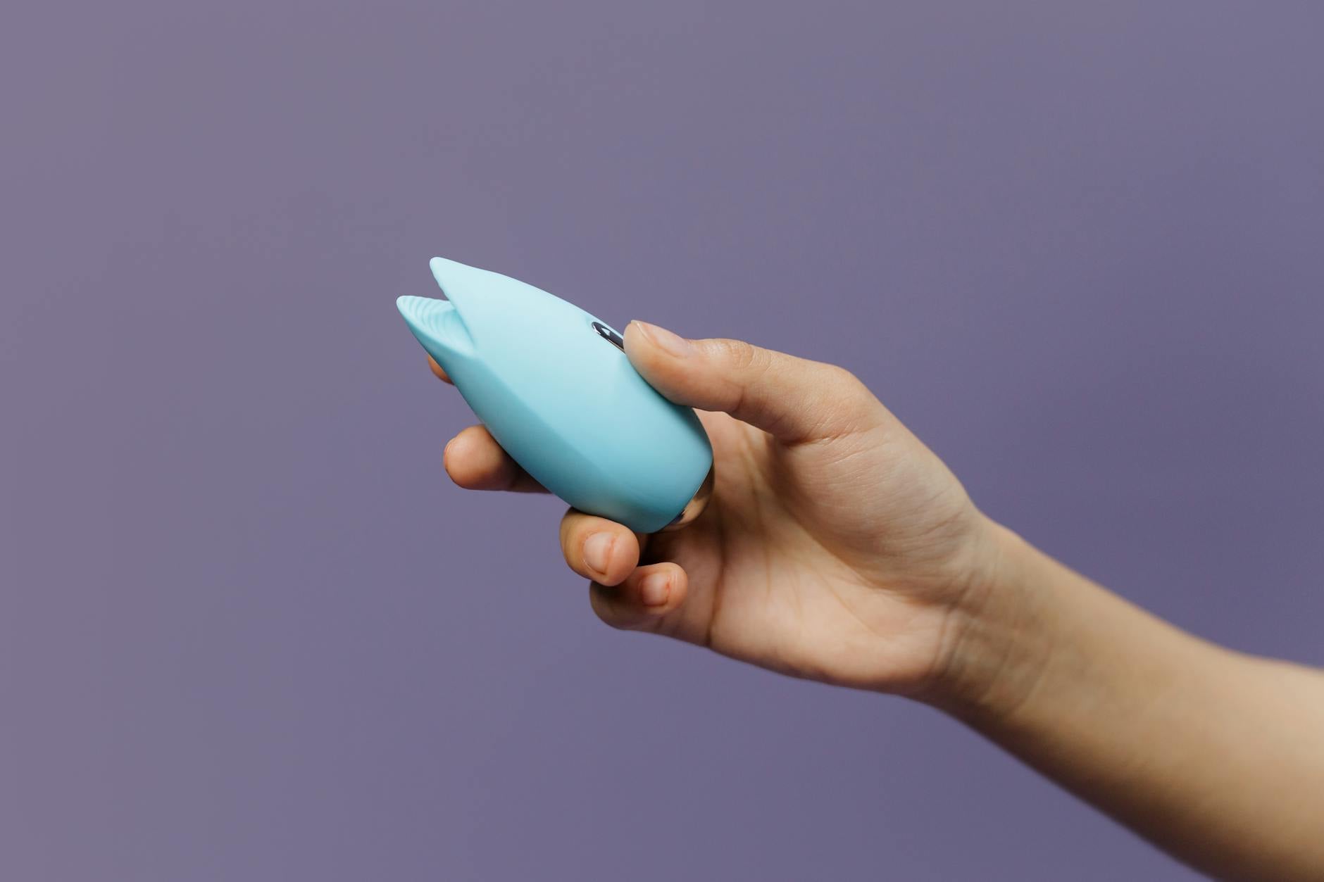 Hand holding a fresh lemon against a soft pink background, symbolizing new beginnings and renewal